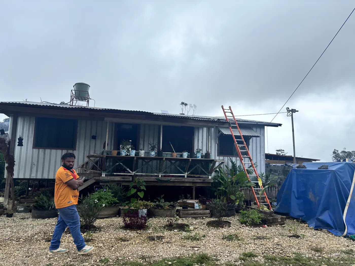 GPS360 technician surveying a highlands building for a Starlink installation, ladder in place against the roofline